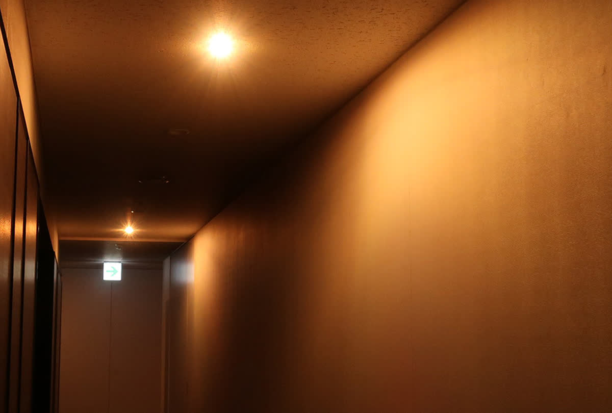 Corridor at night under emergency lighting with a warm glow and a visible exit indicator at the end